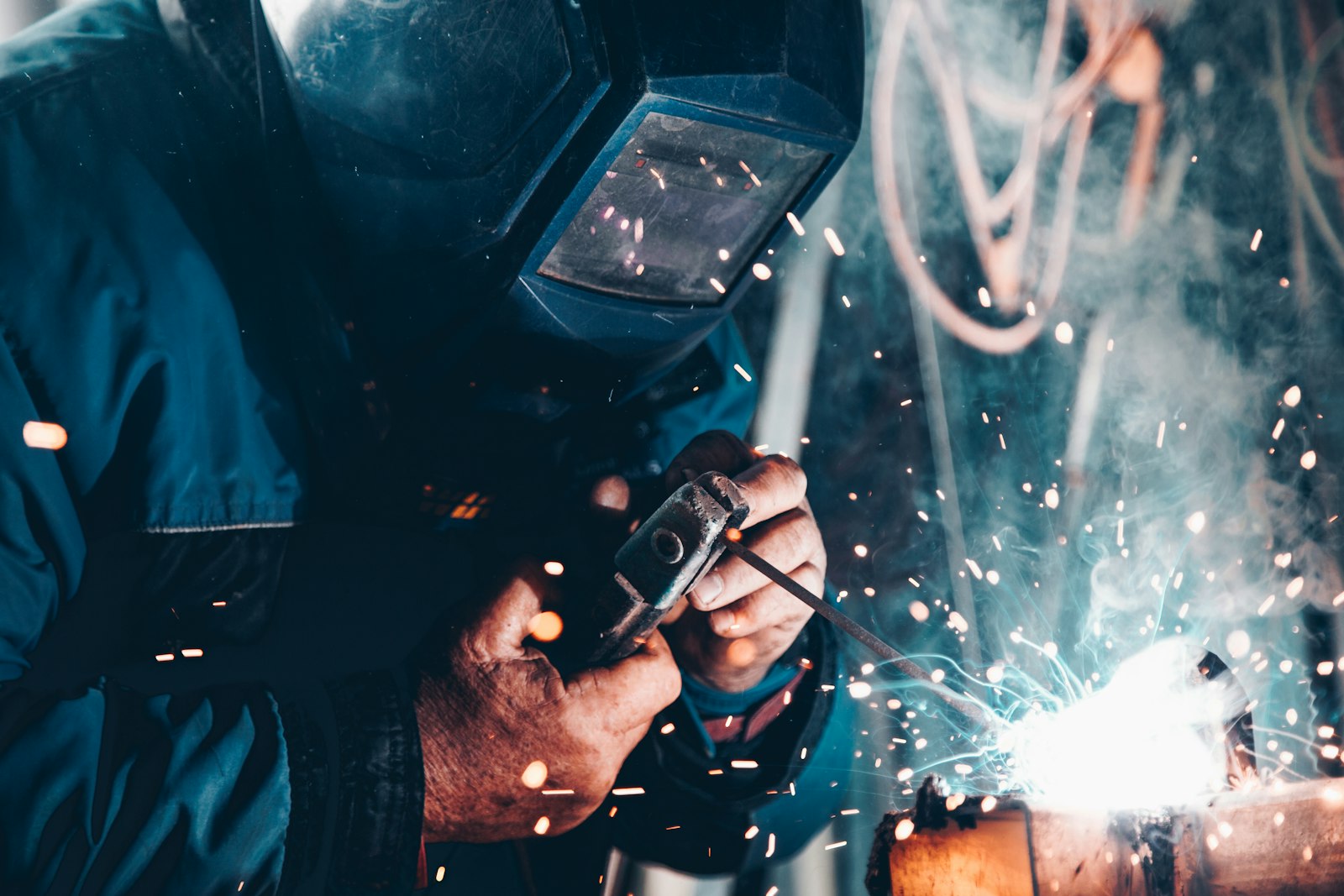 Welder working on steel with sparks in an industrial shop